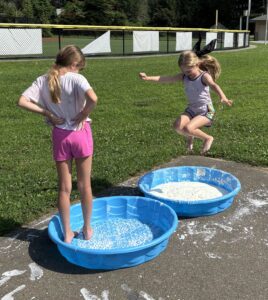 Girls jumping into kiddie pools for STEM activity